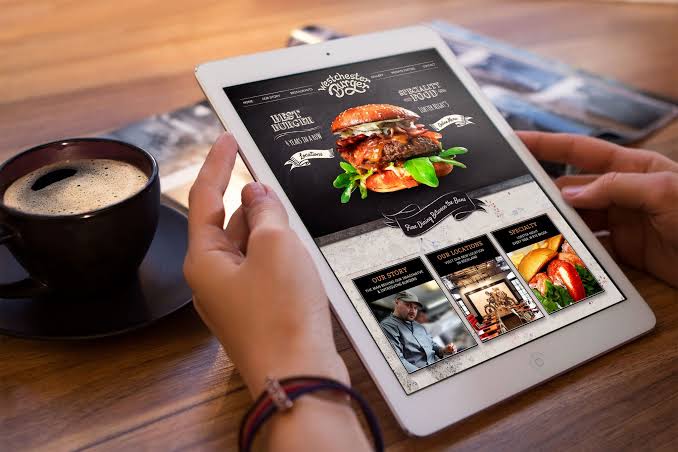 Cliente a navegar num menu digital de hambúrgueres num tablet moderno